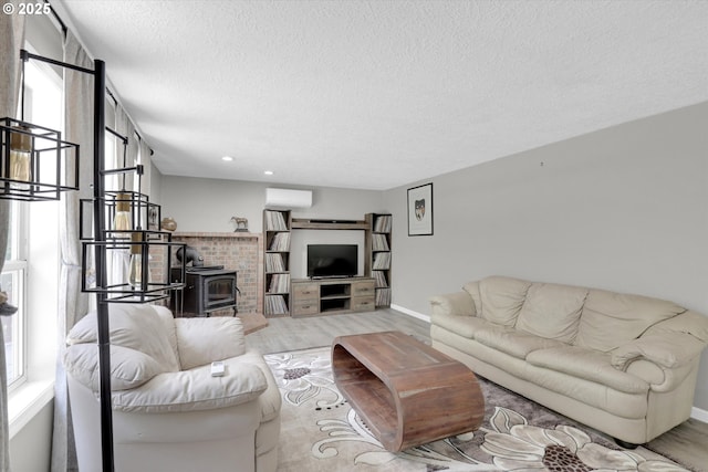 14011 NE 346th St, Battle Ground, WA 98604 - living area featuring wood finished floors, a textured ceiling, a wood stove, an AC wall unit, and baseboards