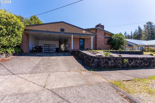 176 N Henry St, Coquille, OR 97423 - view of front of house featuring driveway, a chimney, brick siding, and a carport