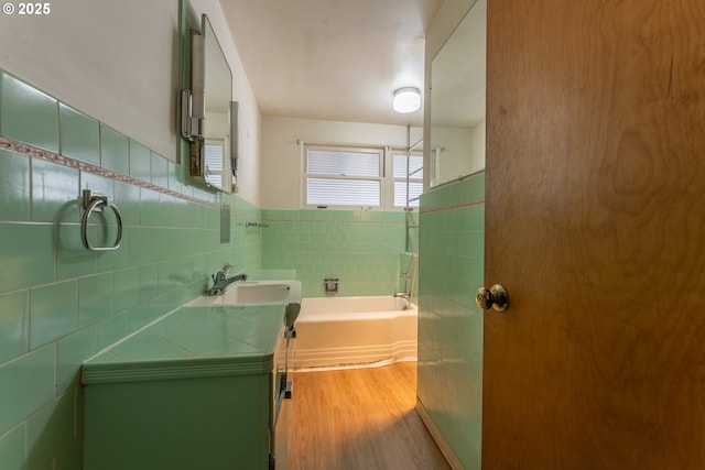 176 N Henry St, Coquille, OR 97423 - bathroom featuring tile walls, wood finished floors, a tub to relax in, vanity, and a wainscoted wall