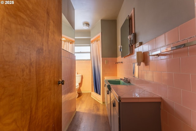 176 N Henry St, Coquille, OR 97423 - bathroom featuring toilet, tile walls, wood finished floors, vanity, and wainscoting