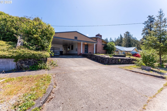 176 N Henry St, Coquille, OR 97423 - view of front of property with asphalt driveway, a carport, brick siding, and a chimney