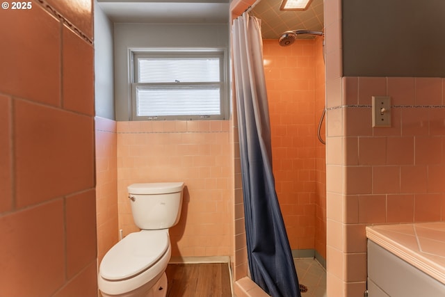 176 N Henry St, Coquille, OR 97423 - bathroom with a tile shower, tile walls, wood finished floors, and toilet