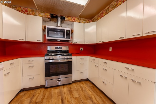 176 N Henry St, Coquille, OR 97423 - kitchen with appliances with stainless steel finishes, light wood-style floors, and white cabinetry