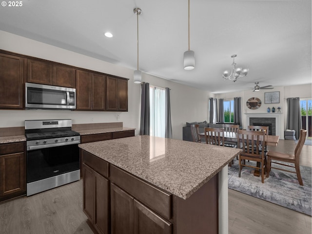 1053 Winfield St NE, Gervais, OR 97026 - kitchen with stainless steel appliances, light wood-type flooring, dark brown cabinets, a chandelier, and a kitchen island