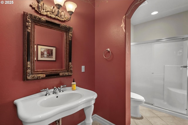 bathroom with a shower stall, tile patterned flooring, toilet, a sink, and baseboards