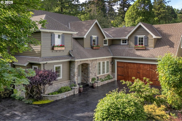 view of front of property with stone siding, roof with shingles, and concrete driveway