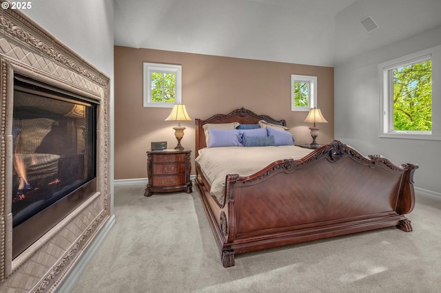 bedroom with light colored carpet, lofted ceiling, multiple windows, and baseboards
