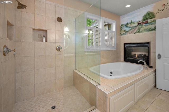 bathroom featuring a tile shower, a tub with jets, tile patterned floors, a tile fireplace, and recessed lighting
