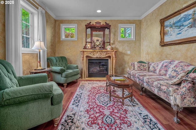 living area featuring wood finished floors, a glass covered fireplace, and ornamental molding