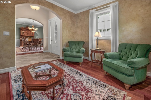 sitting room with arched walkways, crown molding, a chandelier, baseboards, and wood finished floors