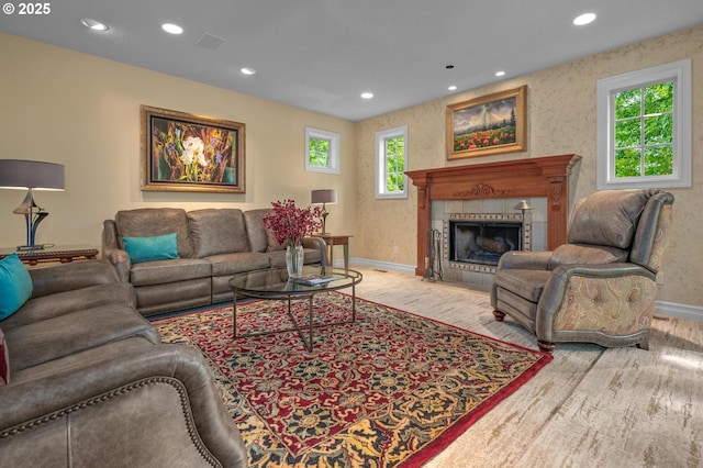living area featuring baseboards, recessed lighting, wood finished floors, and a tiled fireplace