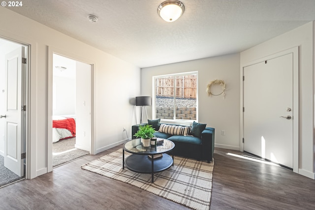 living area with wood finished floors, baseboards, and a textured ceiling