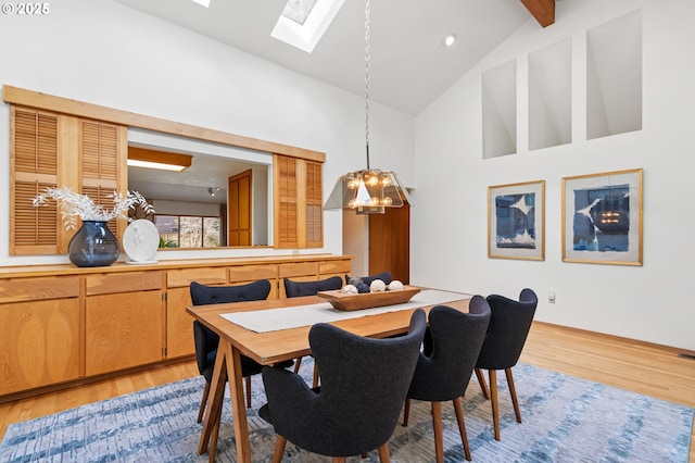 dining space with beam ceiling, high vaulted ceiling, and light wood finished floors