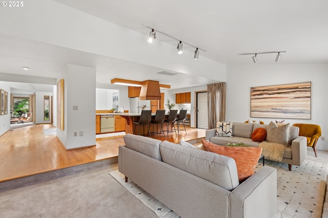 living area with visible vents, light wood-style floors, and vaulted ceiling