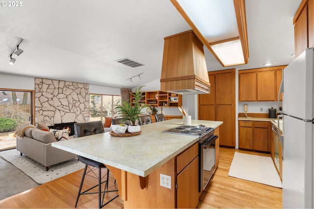 kitchen featuring visible vents, custom range hood, electric stove, freestanding refrigerator, and light wood finished floors