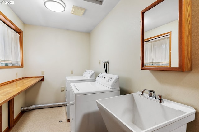 clothes washing area featuring a sink, tile patterned floors, laundry area, and washer and clothes dryer