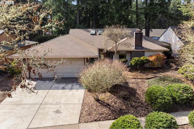 single story home with an attached garage, a chimney, driveway, and a shingled roof