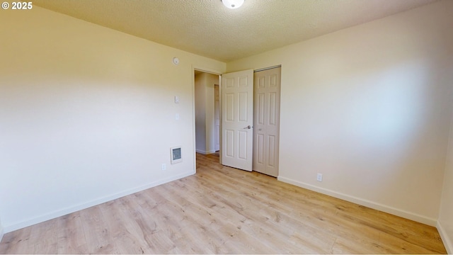 unfurnished bedroom with baseboards, a textured ceiling, wood finished floors, and a closet