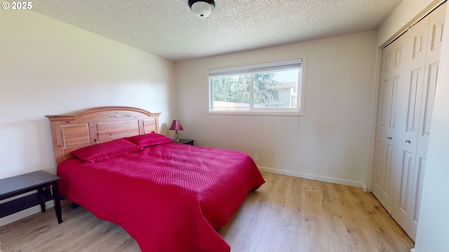 bedroom featuring baseboards, a textured ceiling, wood finished floors, and a closet