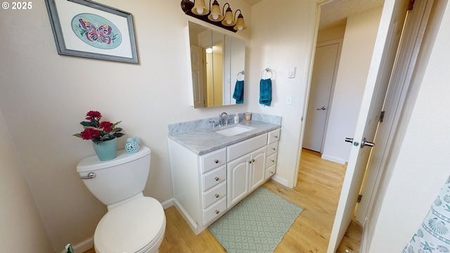 bathroom with baseboards, vanity, toilet, and wood finished floors