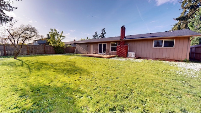 back of property featuring a lawn, a deck, a chimney, and a fenced backyard