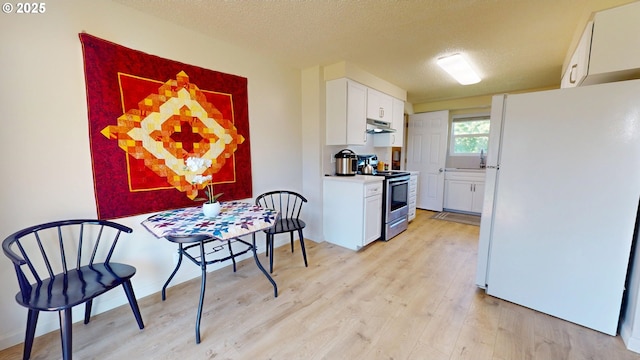 kitchen with electric range, a textured ceiling, freestanding refrigerator, light wood-type flooring, and under cabinet range hood