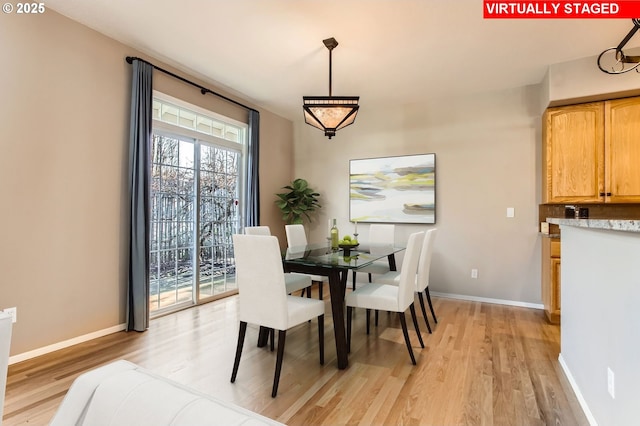 dining room featuring light wood finished floors and baseboards