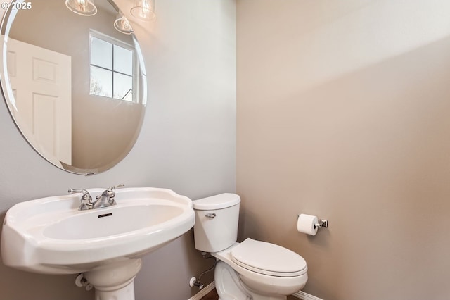 half bathroom featuring a sink, toilet, and baseboards