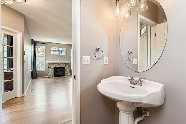 bathroom featuring a stone fireplace, wood finished floors, visible vents, and baseboards