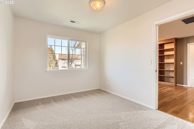 carpeted spare room featuring baseboards and visible vents