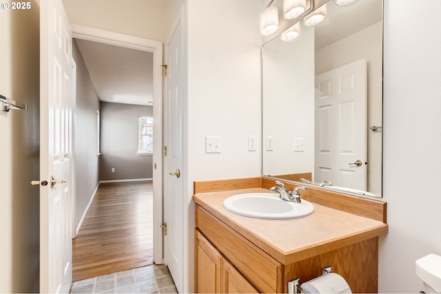 bathroom with toilet, baseboards, and vanity