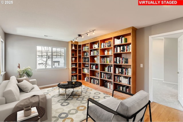 sitting room featuring light wood-type flooring, rail lighting, and baseboards