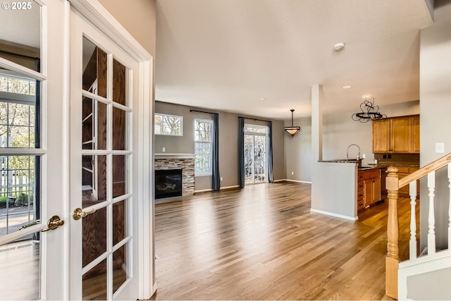 foyer entrance featuring light wood-type flooring, baseboards, and a glass covered fireplace