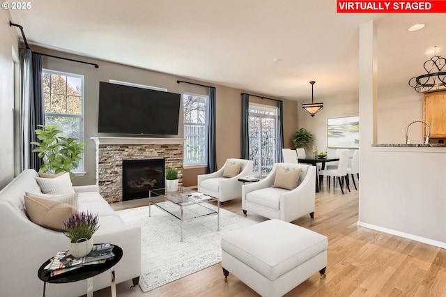 living room featuring a fireplace, light wood-style flooring, and baseboards