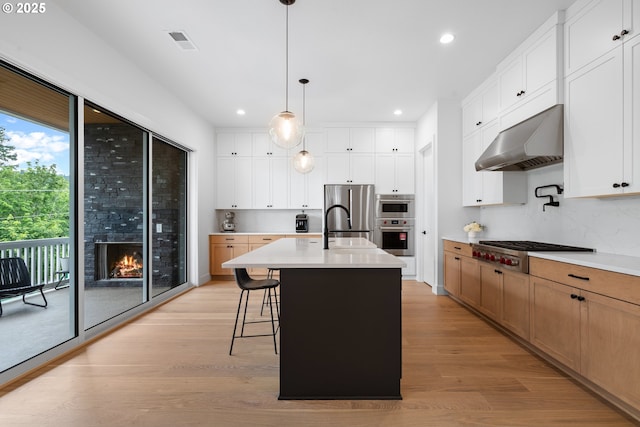 15625 NW Gooderham St, Portland, OR 97229 - kitchen featuring exhaust hood, appliances with stainless steel finishes, recessed lighting, light wood-type flooring, and light countertops