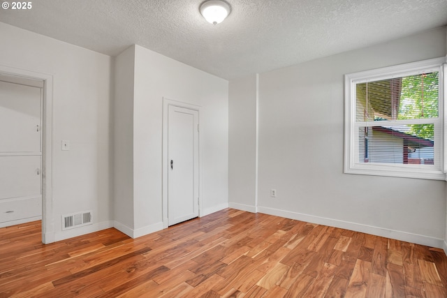 unfurnished bedroom with light wood finished floors, baseboards, visible vents, and a textured ceiling