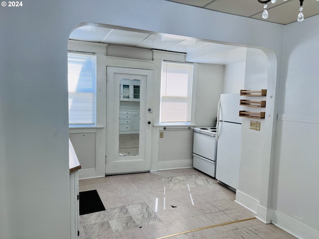 kitchen with white appliances, baseboards, and arched walkways