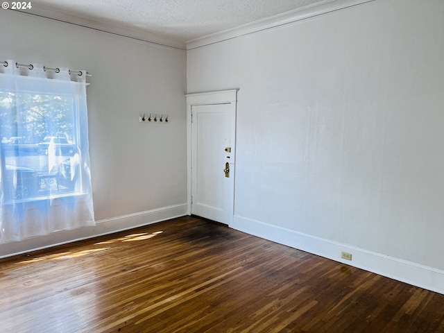 empty room with dark wood-style floors, crown molding, a textured ceiling, and baseboards