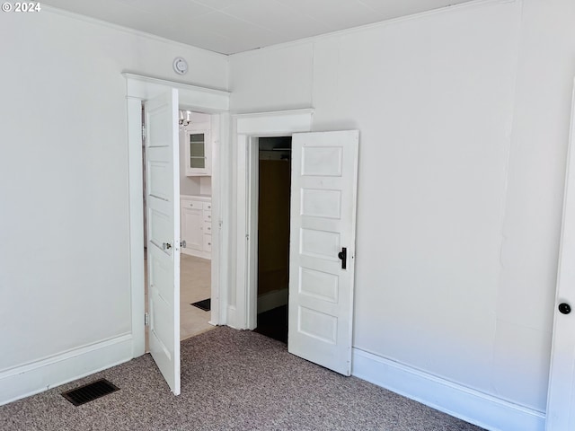 unfurnished bedroom featuring carpet floors, visible vents, and crown molding