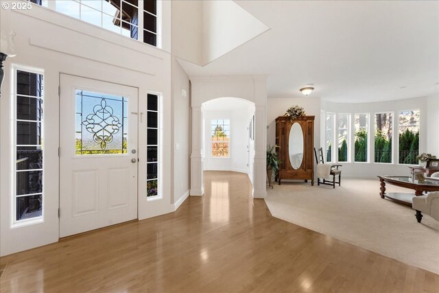 13658 SE Snowfire Dr, Happy Valley, OR 97086 - foyer featuring decorative columns, plenty of natural light, arched walkways, wood finished floors, and a high ceiling