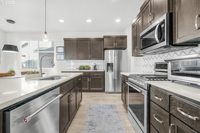 kitchen featuring decorative light fixtures, tasteful backsplash, sink, stainless steel appliances, and dark brown cabinets