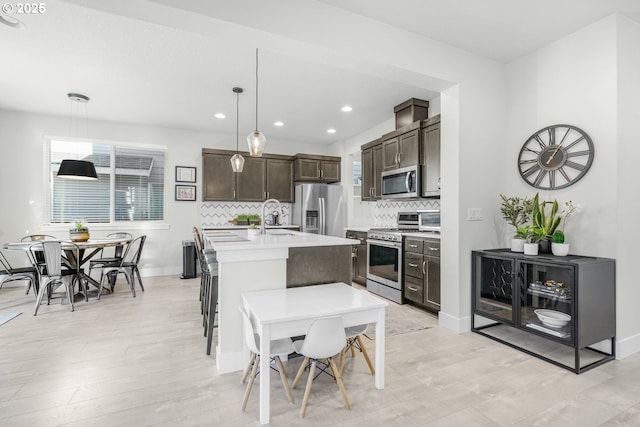 kitchen featuring pendant lighting, sink, a kitchen island with sink, dark brown cabinets, and stainless steel appliances