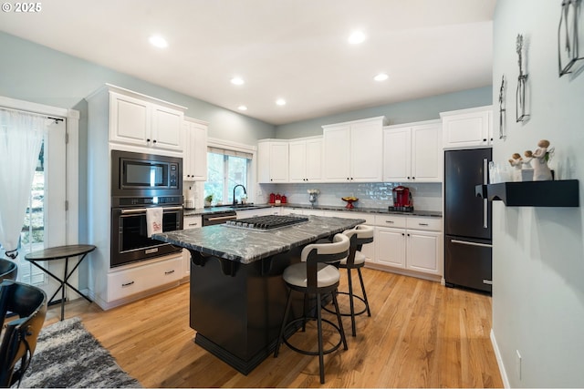 16420 SW Sienna Ln, Beaverton, OR 97007 - kitchen featuring black appliances, white cabinets, light wood-type flooring, and recessed lighting