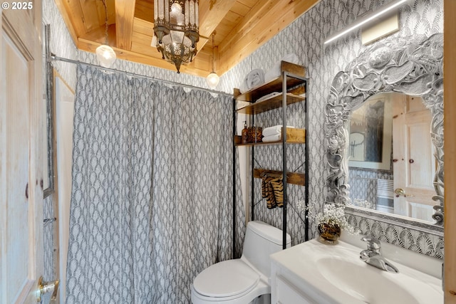 53461 Safe Rd, Bandon, OR 97411 - full bathroom with wallpapered walls, toilet, vanity, beamed ceiling, and wood ceiling