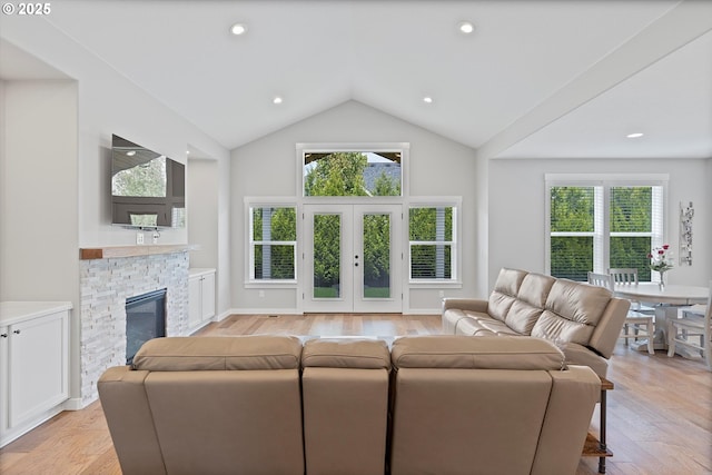 living area with a stone fireplace, recessed lighting, light wood finished floors, and vaulted ceiling