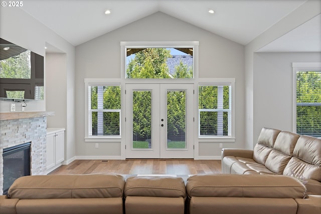 living room with a wealth of natural light, light wood-type flooring, and lofted ceiling