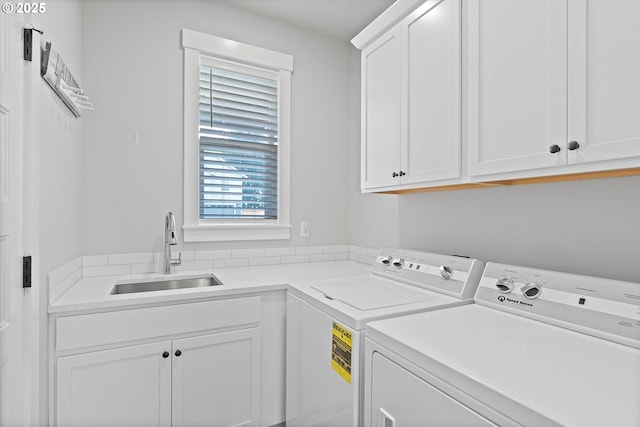 laundry area featuring cabinet space, separate washer and dryer, and a sink