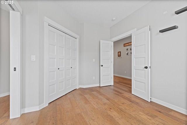 unfurnished bedroom featuring baseboards, a closet, and light wood-type flooring