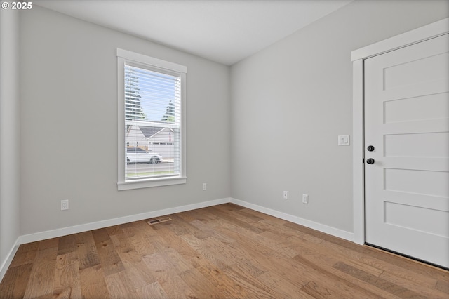 empty room featuring baseboards, wood finished floors, and visible vents
