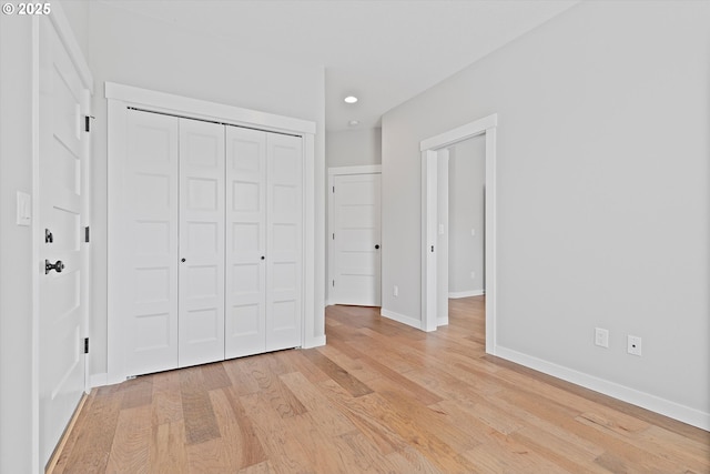 unfurnished bedroom with light wood-type flooring, recessed lighting, baseboards, and a closet